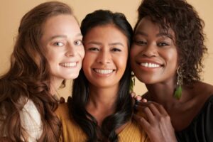 Trois jeunes femmes de couleurs différentes souriantes