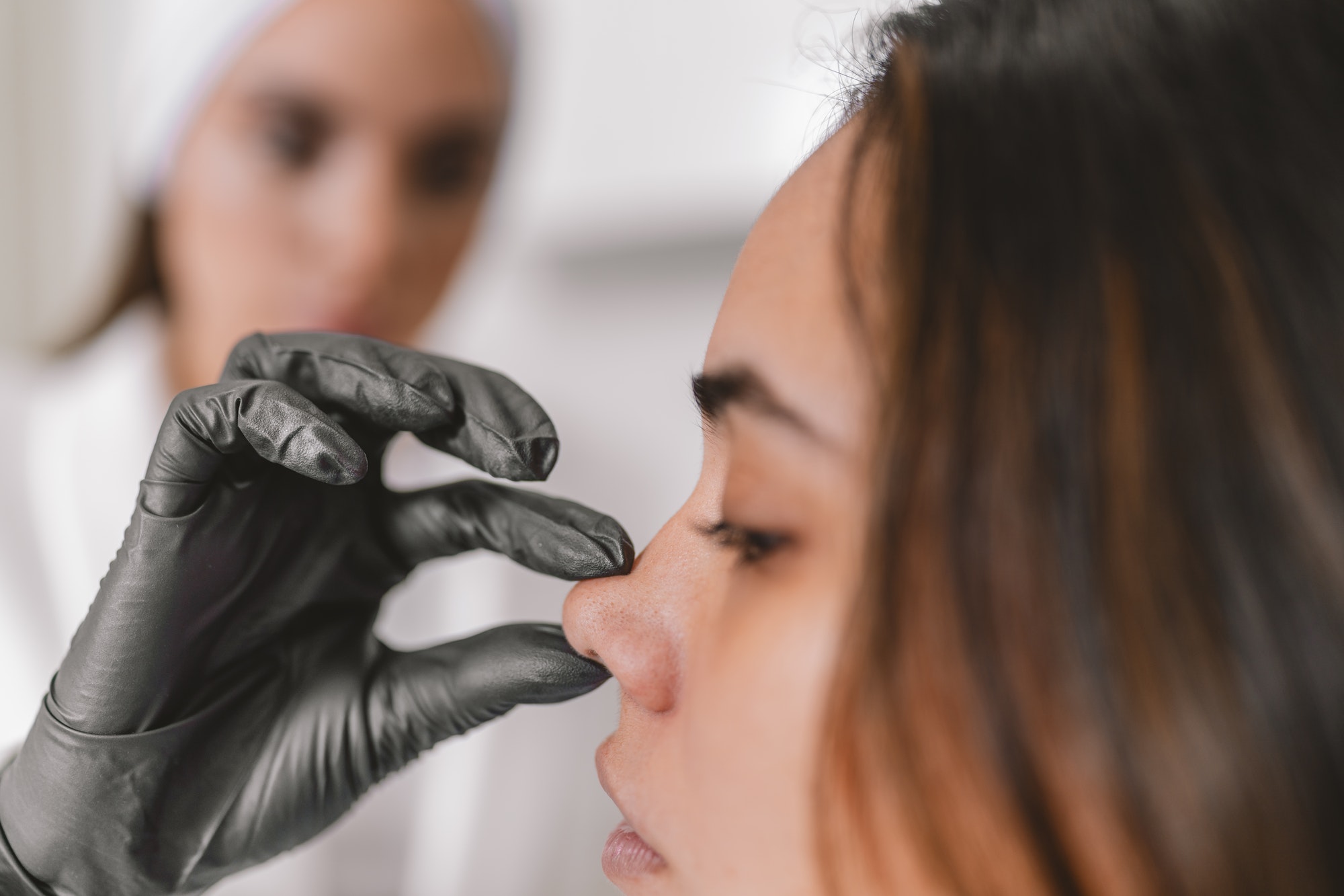 Woman in a cosmetic surgery clinic examining her nose